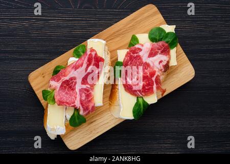 Ansicht von oben der Camembert Sandwich mit geräuchertem Speck auf dunklen Holztisch. Stockfoto