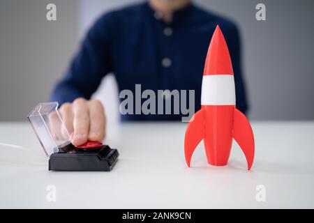 Der Geschäftsmann Hand mit Raketen durch Drücken der roten Taste Stockfoto