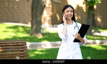 Lächelnd Krankenschwester sprechen Telefon mit Patient im Krankenhaus Park, medizinische Versorgung, Gesundheit Stockfoto