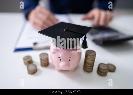 In der Nähe von Piggy Bank tragen Staffelung hat und gestapelte Münzen Vor Unternehmer Stockfoto