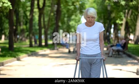 Alte Frau bewegen im Freien mit Gehhilfe, Rehabilitation nach Trauma umgekippt Stockfoto