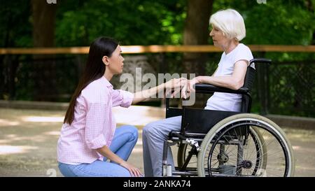 Freiwillige Gespräch mit weinenden Frau im Rollstuhl, psychologische Unterstützung, Park Stockfoto