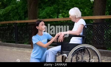 Freiwillige glücklich lächelnd zu den älteren Frau sitzt im Rollstuhl, alte Menschen Pflege Stockfoto