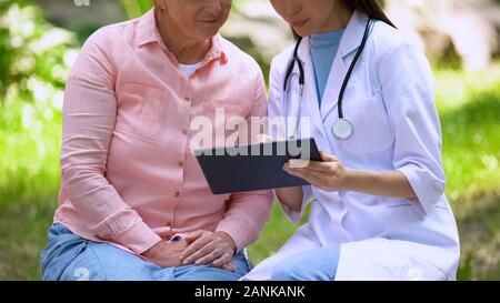 Junger Arzt zeigen Bilder auf Tablet diskutieren Diagnose im Alter von weiblichen Patienten Stockfoto