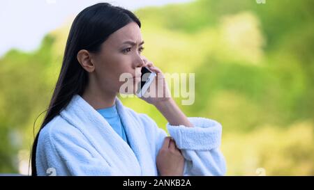 Junge Frau im Bademantel am Telefon sprechen im Freien, betonte der Problem umgekippt Stockfoto