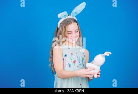 Ruhe und frohe Ostern. Kleines Mädchen und Kaninchen Spielzeug. Kleine Mädchen in Rabbit Ears mit Ostern Spielzeug. Kleines Kind in Osterhasen Stil spielen mit Spielzeug. Kleines Kind mit niedlichen Spielzeug. Osterhase Hase. Stockfoto