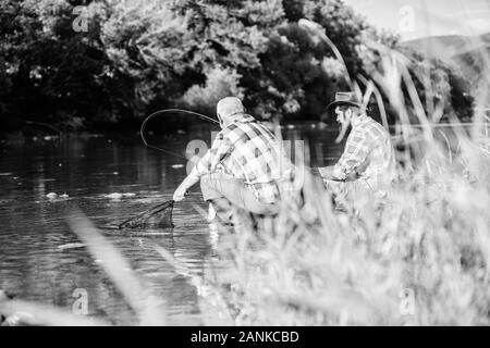 Die wilderei Kriminalität und Lizenz. Schwarzmarkt Kaviar. Wilderer angeln. Die illegale Jagd Kaviar. Auszüge Eier vom Stör gefangen. Trap für Fische. Männer sitzen am Flußufer mit Angelausrüstung. Stockfoto