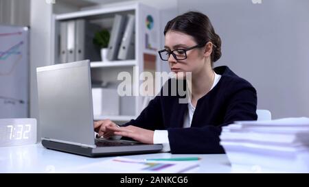 Ernsthafte weibliche Büroangestellte in Brillen Tippen auf Laptop, geschäftigen Lebensstil Stockfoto