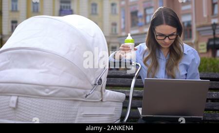 Büro Mitarbeiter kämpfen, arbeiten, die auf Notebook- und achten Sie auf Kind im Kinderwagen Stockfoto