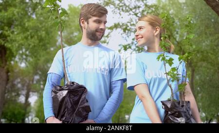 Freiwillige Paar hält Baum Sproß und an jedem anderen suchen, Zweisamkeit Stockfoto