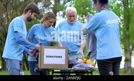 Freiwillige sortieren Kleidung, Spende, philanthropische Organisation Stockfoto