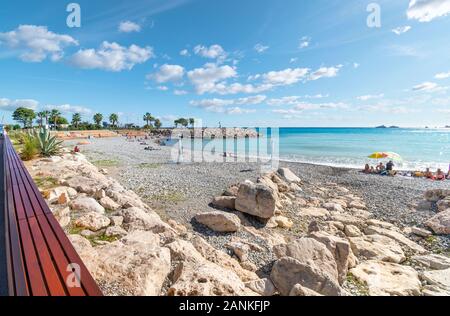 Familien und Touristen genießen einen sonnigen Nachmittag an der französischen Riviera am Plage de Fossan Strand von Menton, Frankreich. Stockfoto