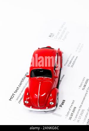 Rotes Volkswagen Beetle Spielzeug mit MOT-Prüfzertifikat. Stockfoto