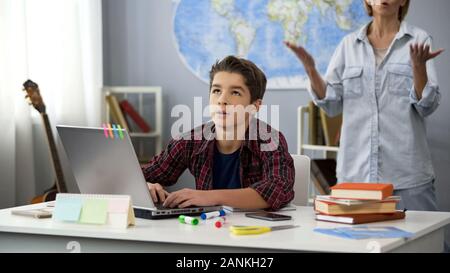 Schüler sitzen laptop Müde von Schelte Mutter hinter stehend, Alter Stockfoto