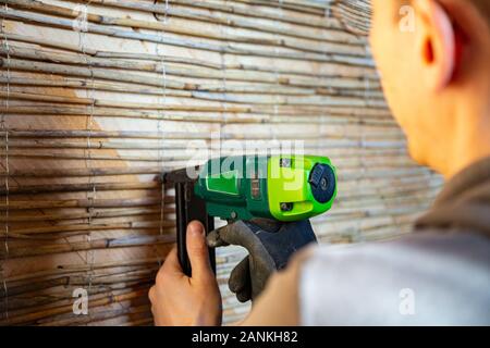 Der Mensch ist das Fixieren reed Mats auf einer Holzwand für plastring die Wände mit Lehm und Sand - Begriff der Moderne und ökologische Architektur vorzubereiten Stockfoto