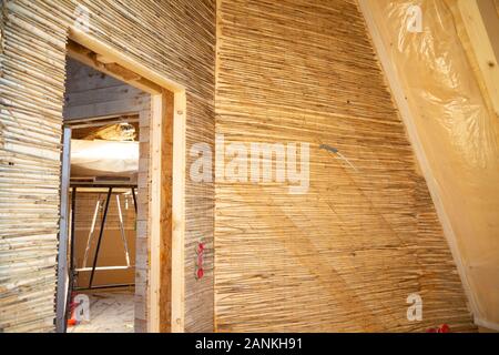 Feste reed Mats auf einer Holzwand für plastring die Wände mit Lehm und Sand - Begriff der Moderne und ökologische Architektur vorbereitet Stockfoto