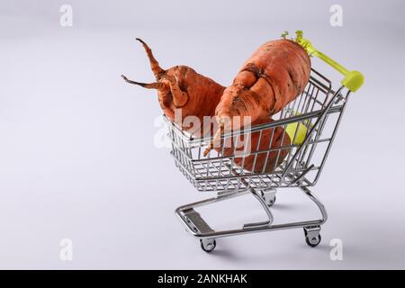 Lebensmittelgeschäft Trolley mit hässlichen Karotte auf weißem Hintergrund. Konzept Umwelt shopping, Kopie Raum Stockfoto