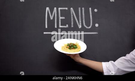 Hand, Teller mit Nudeln auf Menü Hintergrund, leckere Rezepte kochen Stockfoto