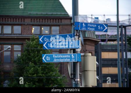 Viele Richtungsschilder, die an einem Pfosten in der Kreuzung in Helsinki angebracht sind und Radfahrern und Fußgängern die Routen zu berühmten Orten zeigen. Stockfoto