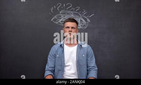 Verwirrt Mann gegen Tafel, auf der Suche nach Antwort, Mangel an Ideen Stockfoto