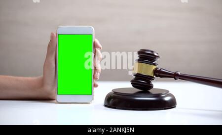 Weibliche Hand smartphone Green Screen, gavel steht auf soliden Block, App Stockfoto