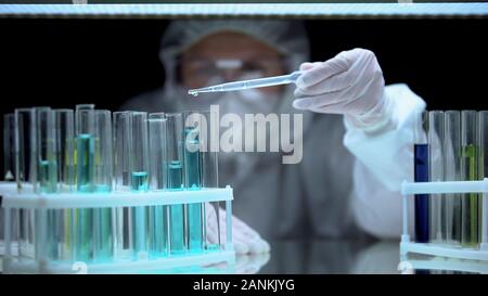 Professionelle lab Worker strömenden Flüssigkeit im Reagenzglas, illegale Versuche, Verbrechen Stockfoto