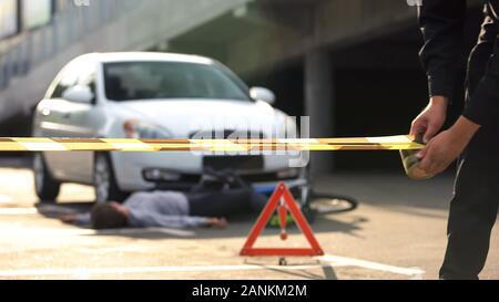 Polizist abrollen Vorsicht Band an der Unfallstelle, Warnschild, Kriminalität Stockfoto