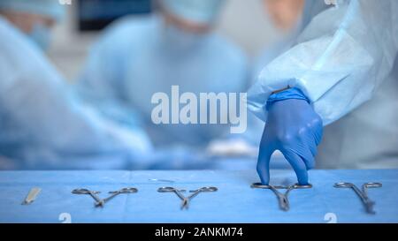 Die Hände des Chirurgen Assistant unter sterilen medizinischen Geräten aus Tabelle, Klinik Stockfoto