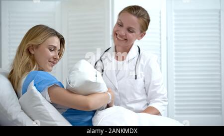 Happy Mother holding newborn baby, lächelnd Arzt am Kind suchen, Mutterschaft Stockfoto