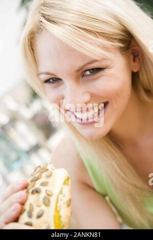 Fröhliche junge Frau hält ein Brötchen - glückliche junge Frau mit Brötchen Stockfoto