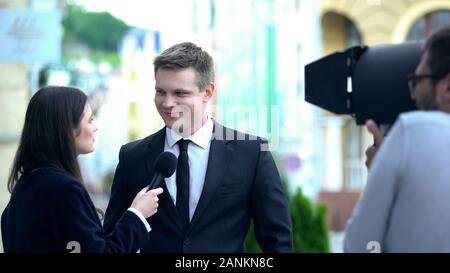 Lächelnde Politiker geben Interview mit TV-Journalist, Operator Recording Live Stockfoto