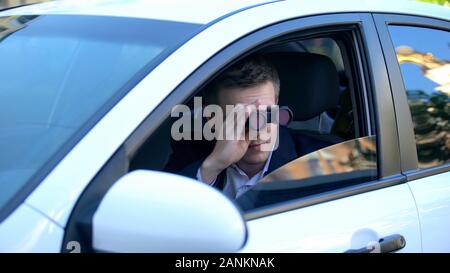Mann in Anzug Spionage aus dem Auto über Ferngläser, Privatdetektiv Untersuchung Stockfoto