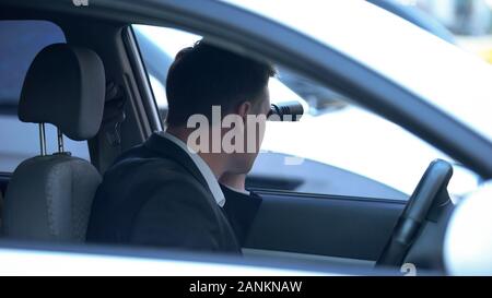 Secret spy im Auto Blick durch ein Fernglas, vertrauliche Informationen suchen Stockfoto