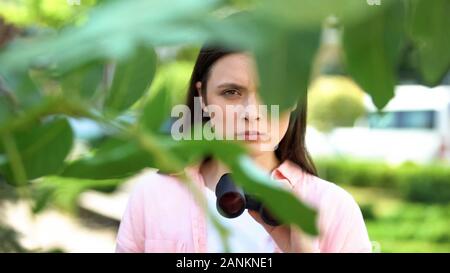 Ernsthafte lady Detective mit Fernglas versteckt sich hinter Park, privates Untersuchung Stockfoto