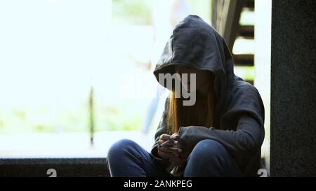 Jugendmädchen in Hoodie heimlich rauchen Zigarette auf der Treppe, Depression beleidigt Stockfoto