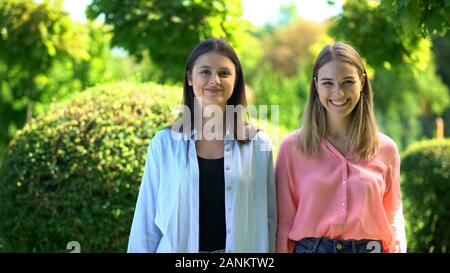 Hübsche junge Frauen lächelnd auf Kamera, gerne weibliche Freunde, freundliche Studenten Stockfoto