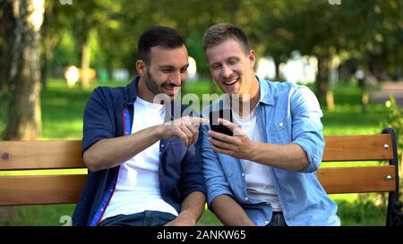 Beste männliche Freunde ansehen Fotos auf Smartphone, Spaß im Park zusammen Stockfoto