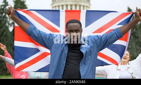 Böse schwarze Mann anheben Großbritannien Flagge, brexit Protest, Migration Krise Stockfoto