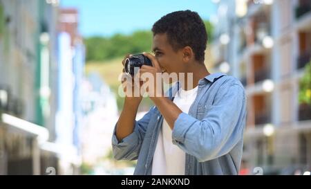 Fröhliche african american Guy die Fotos auf der Kamera im Freien, Hobby Stockfoto