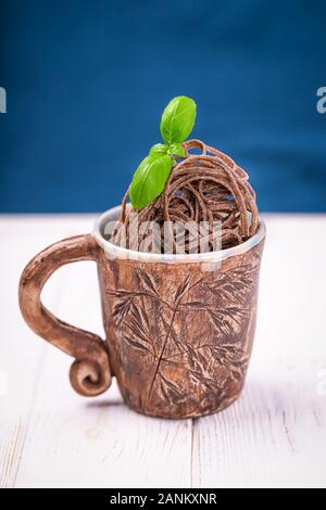 Braun roher Buchweizen nudeln Nudeln in einem keramischen Cup auf dem klassischen blauen Hintergrund. Glutenfreie Konzept. Platz kopieren Stockfoto