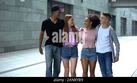 Positive Gruppe junger Menschen umarmen Walking Street, Freundschaft miteinander Stockfoto