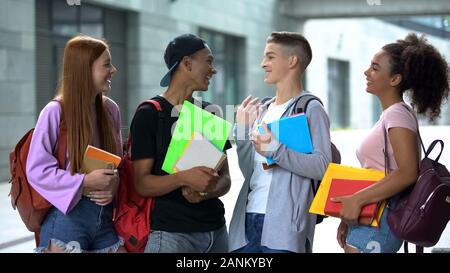 High School Mitschüler mit Notebooks und Rucksäcke sprechen Campus, academy Stockfoto
