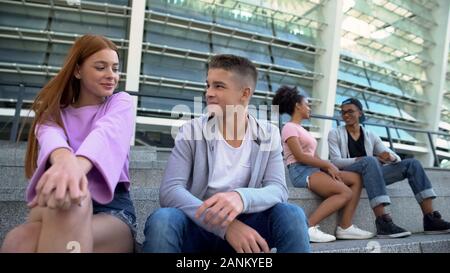 Die jungen Studenten auf im Freien Datum sprechen sitzen Campus Treppen, flirten Stockfoto