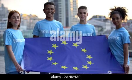Junge multi-rassischen Freiwillige, die Fahne der Europäischen Union, internationale Einheit Stockfoto