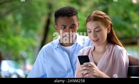 Gemischte schockiert - Rennen teen Paar beobachten soziales Netzwerk Fotos per Telefon Stockfoto