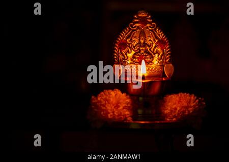 Lit diya Lampe gegen den dunklen Hintergrund. Lampe aus silber Metall mit Gott Statue während Festival lit. Stockfoto