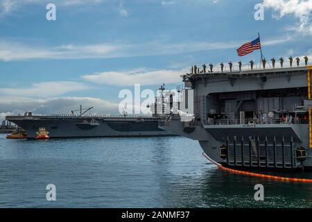 200118 folgt-N-SS 350-1149 SAN DIEGO (Jan. 17, 2020) Matrosen an Bord der Nimitz-Klasse Flugzeugträger USS Nimitz (CVN 68), Recht, Mann, die Schienen und die Ehrungen der Nimitz-Klasse Flugzeugträger USS Theodore Roosevelt (CVN 71), wie er aus seinen Liegeplatz im Hafen von San Diego für die Bereitstellung gezogen wird. Die Theodore Roosevelt Carrier Strike Group ist auf eine regelmäßige Indopazifik Bereitstellung andauernden Frieden, Sicherheit und Stabilität in der gesamten pazifischen Theater der Operationen zu fördern. Stockfoto