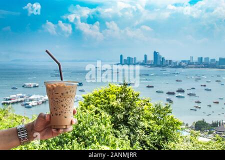 Hand, Eiskaffee und Meer mit viele Boote an der Pattaya in Thailand. Stockfoto
