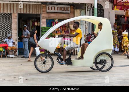 Pointe-à-Pitre, Guadeloupe - Dezember 14, 2018: ein Mann reitet einen Dreirädrigen fahrradrikscha mit Frau an Bord, die durch die Straßen von Pointe-à-Pitre, in Stockfoto