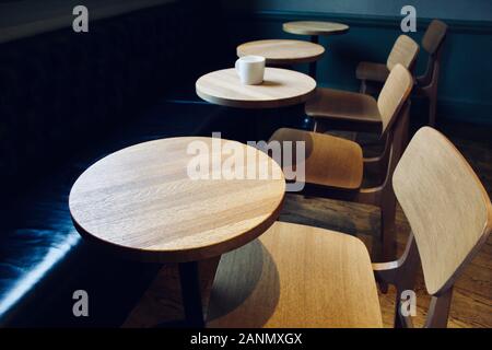 Holztische und Stühle mit Kaffeebecher in einem Leeren Café Stockfoto